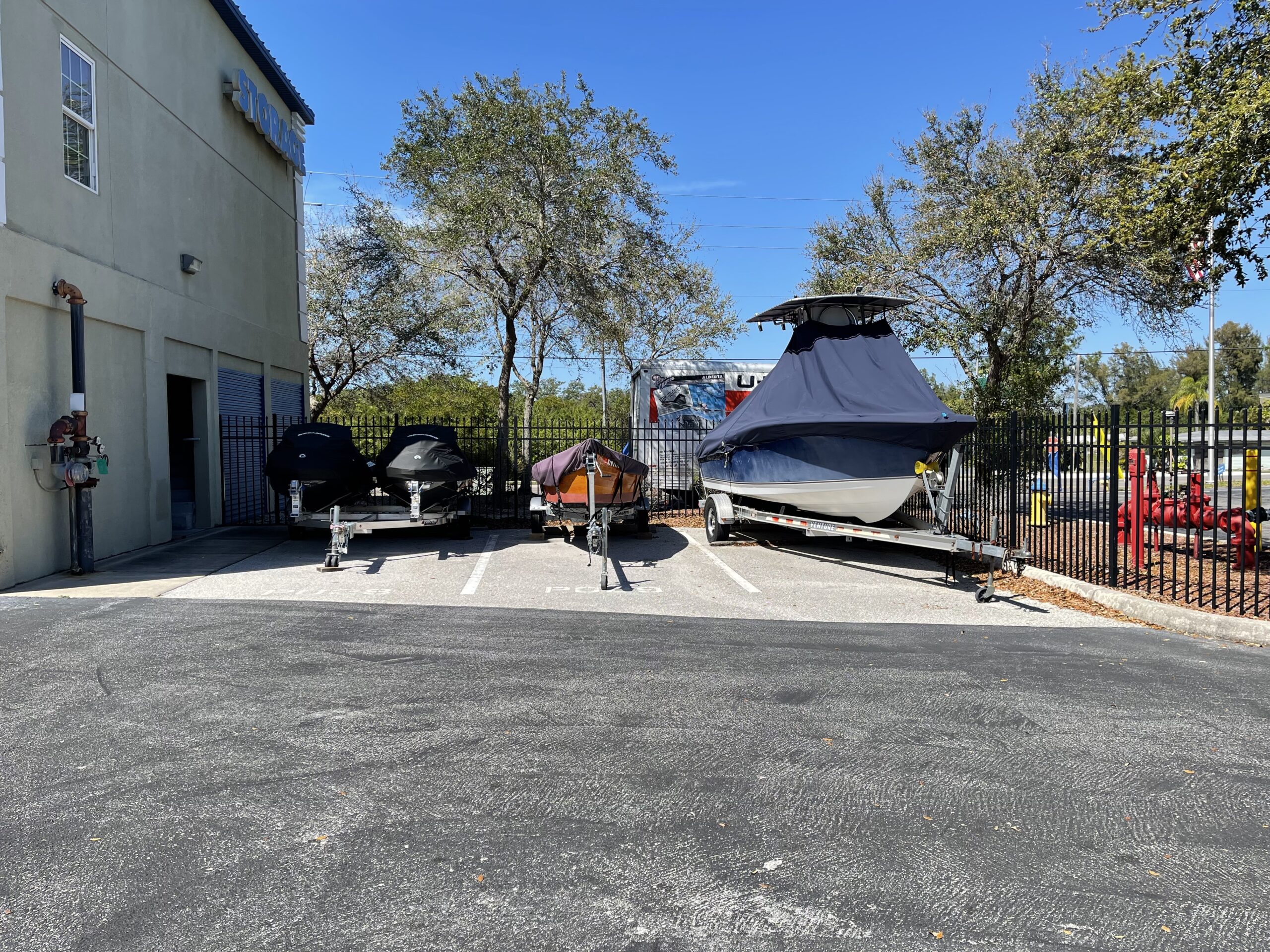 Two jet skis, a fishing boat, and a speed boat in outdoor parking spots.