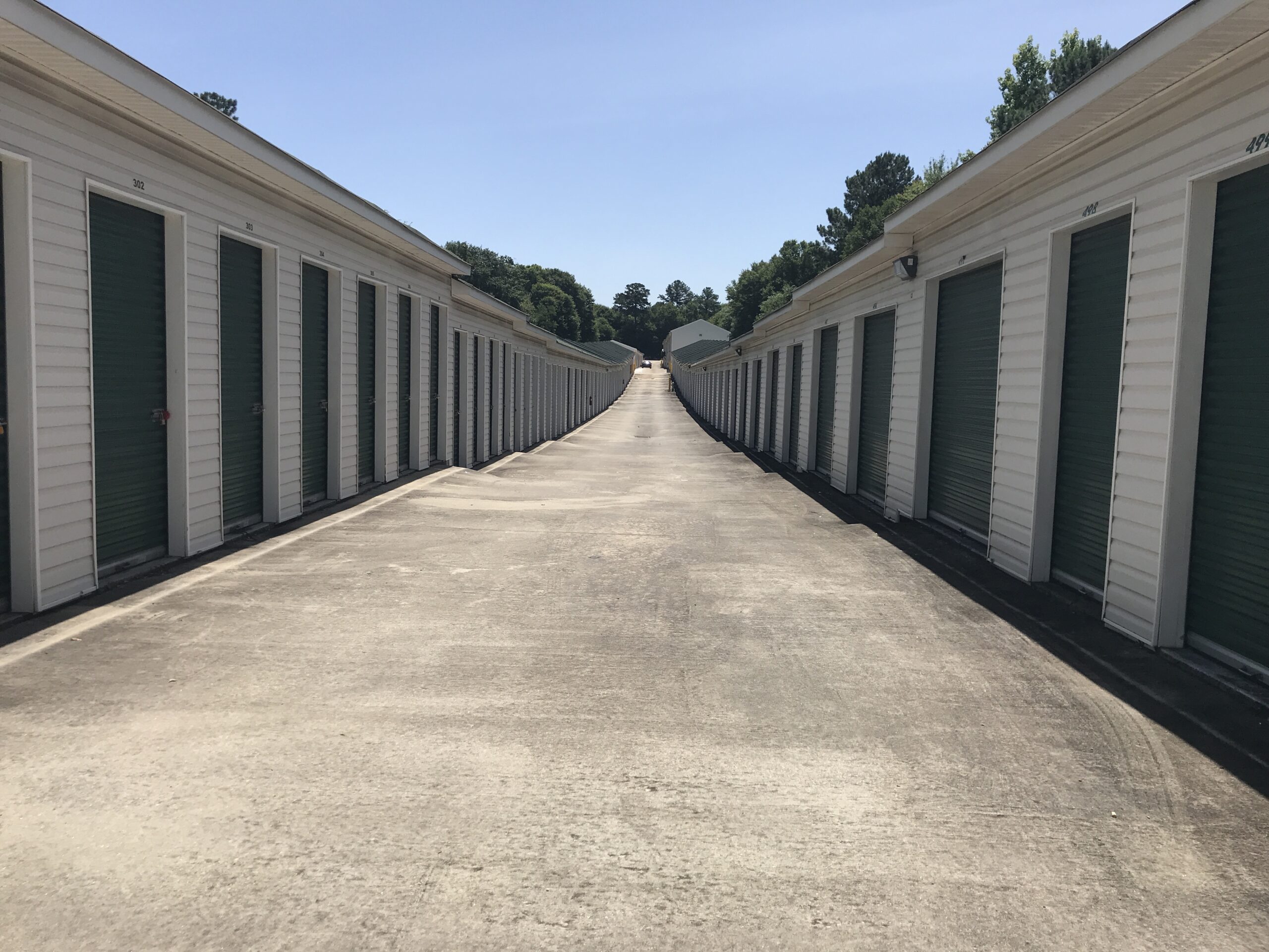 Multiple drive-up storage units on a long road.