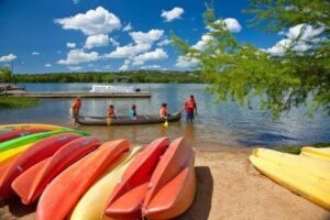 Family kayaking in a lake with kayaks lining the lake shore.