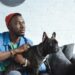 Man holding dog while sitting on a couch.