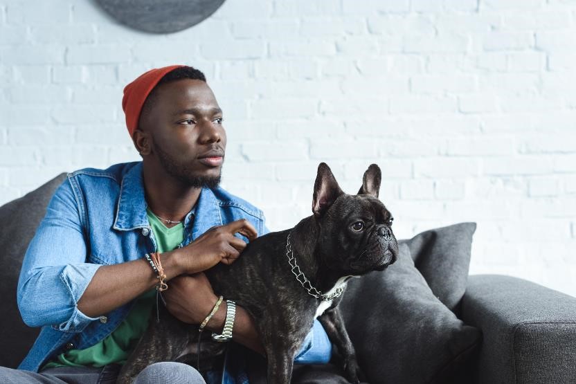 Man holding dog while sitting on a couch.
