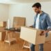 Man smiling while moving boxes out of house.