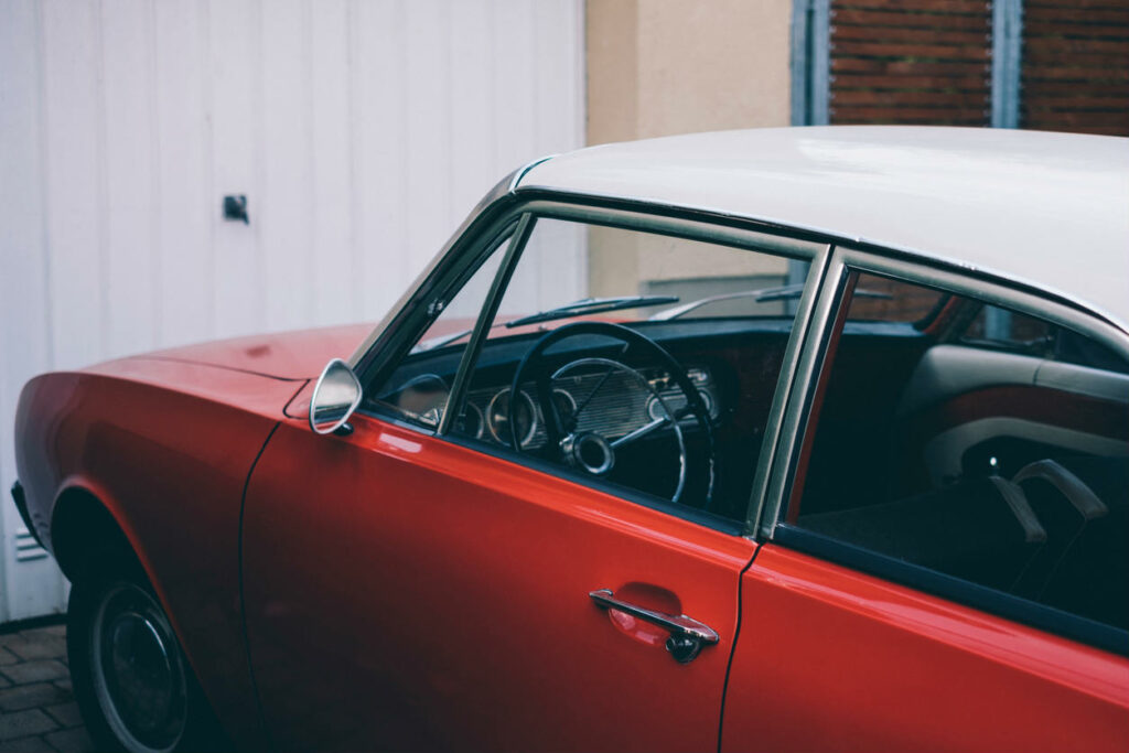 classic red car sitting outside on a driveway
