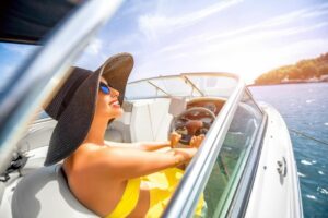 woman in sun hat smiles while on a boat