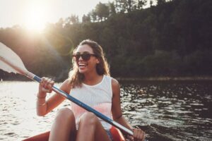 a woman holding a paddle is smiling while kayaking in the water