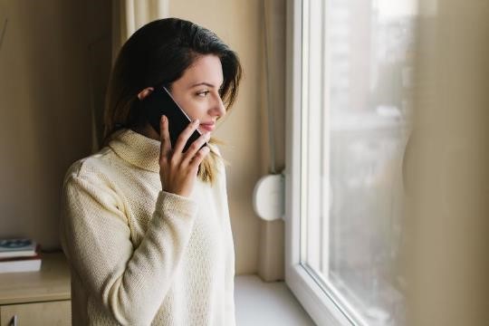 A woman talking on a phone and looking out the window