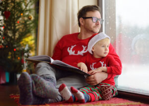 Man holding a baby in Christmas apparel.