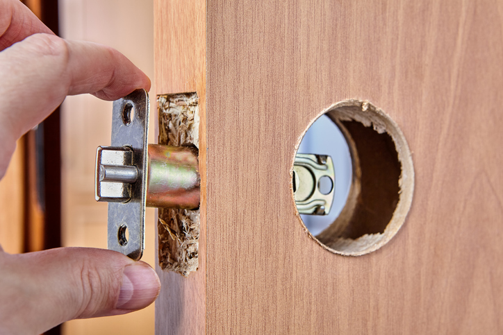A man removing the old door locking mechanism to install a new one for his new house. 