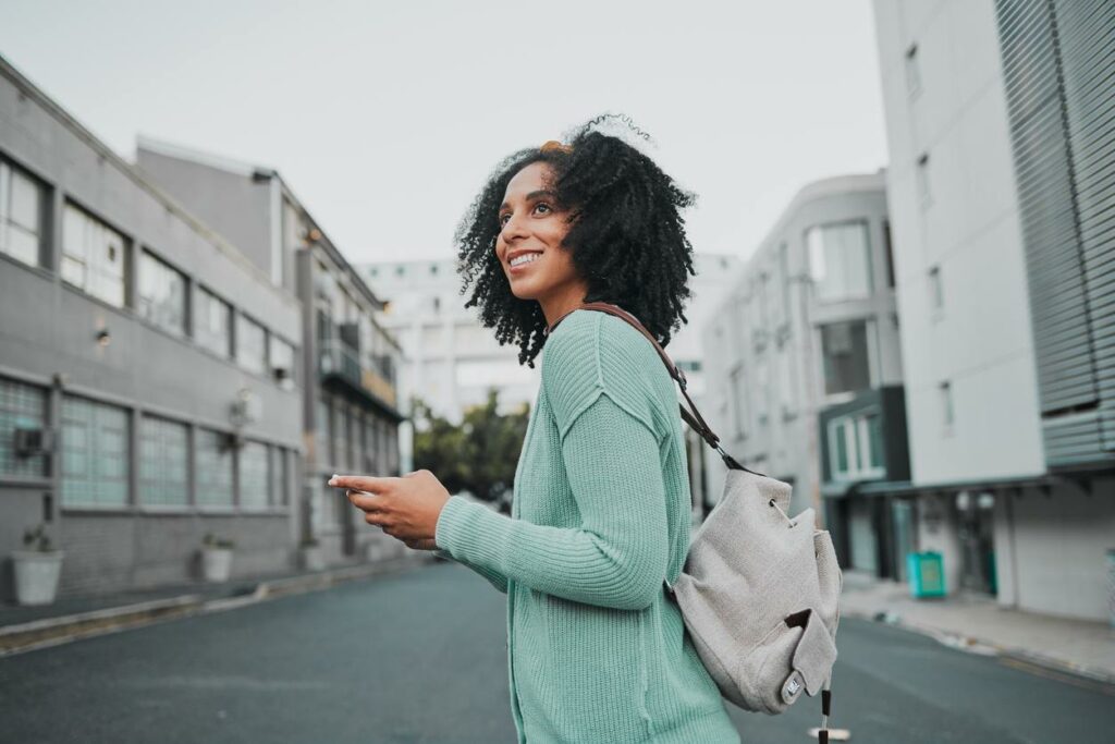 A woman in a green sweater standing in an urban street.