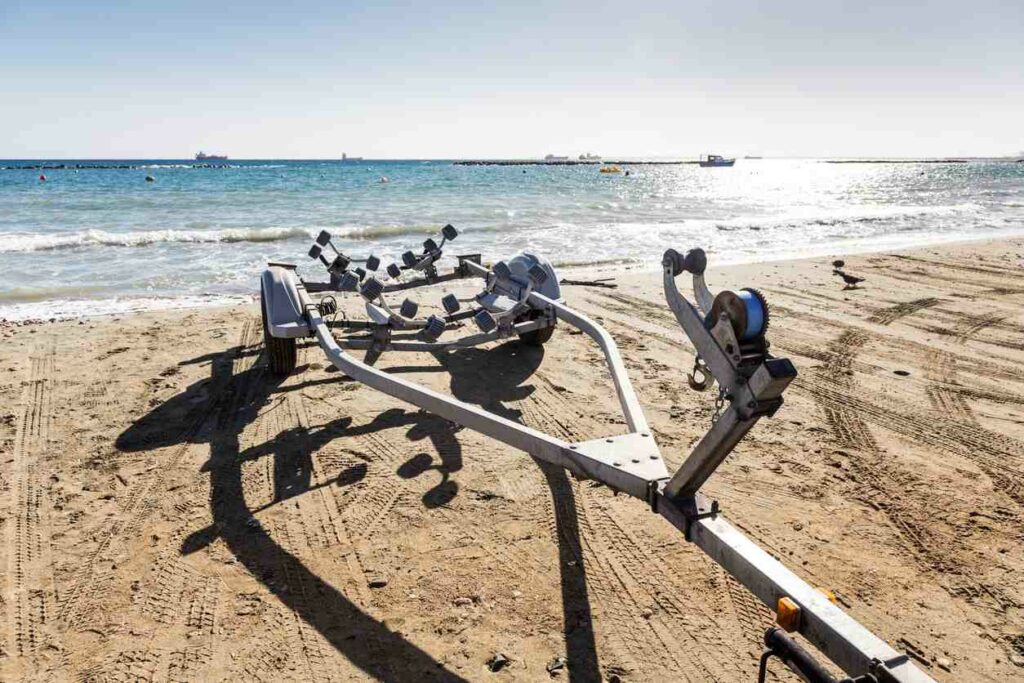 An emptied boat trailer parked right next to a large body of water