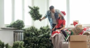 A father and daughter set up a Christmas tree and decorations inside home for the holidays