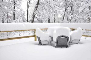 Patio furniture is covered in many inches of bright snow after a snowfall