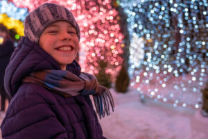 Stock photo of a kid surrounded by Christmas lights.