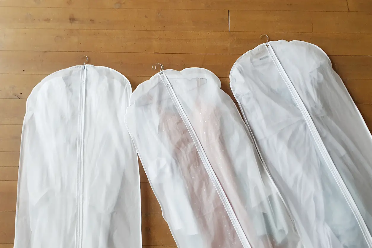 Three wedding dress storage bags lying on a wooden floor, ready to be placed in a unit.