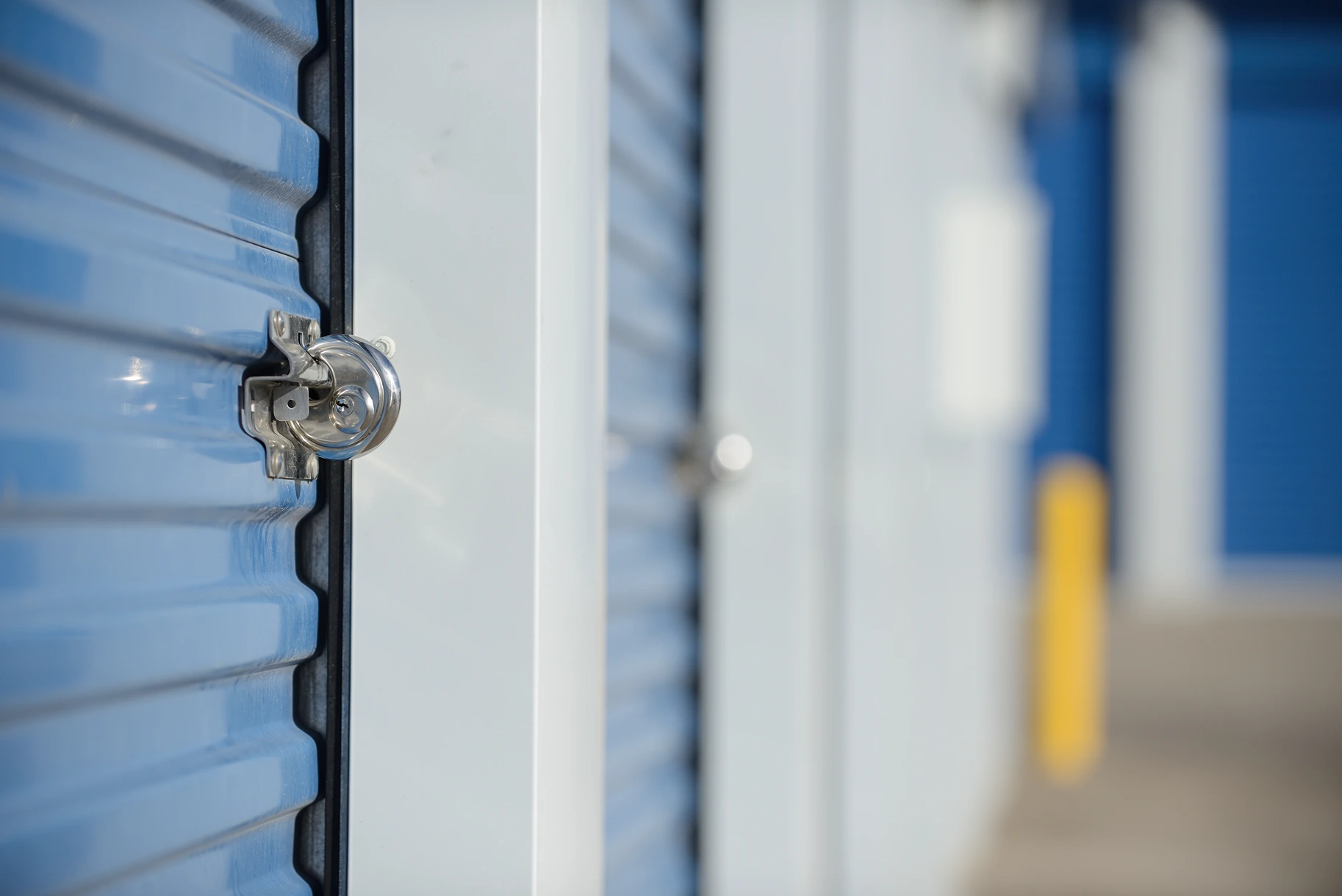 Close-up of a blue storage unit door with a silver lock in focus.