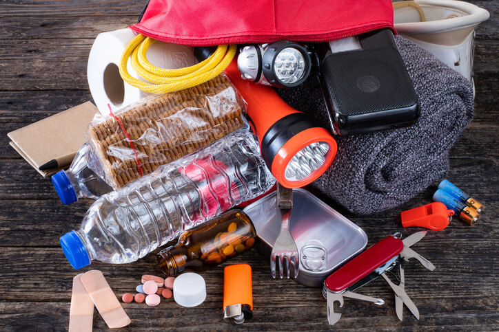 Various emergency supplies for a hurricane, such as bottled water, flashlights, medications, toilet paper, and blankets.