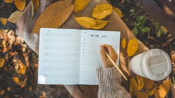 A woman writing down a to-do list as she prepares for the fall.