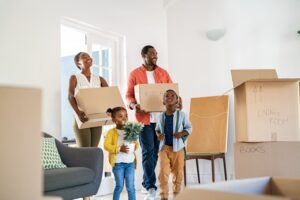 Family with two children moving boxes into new home
