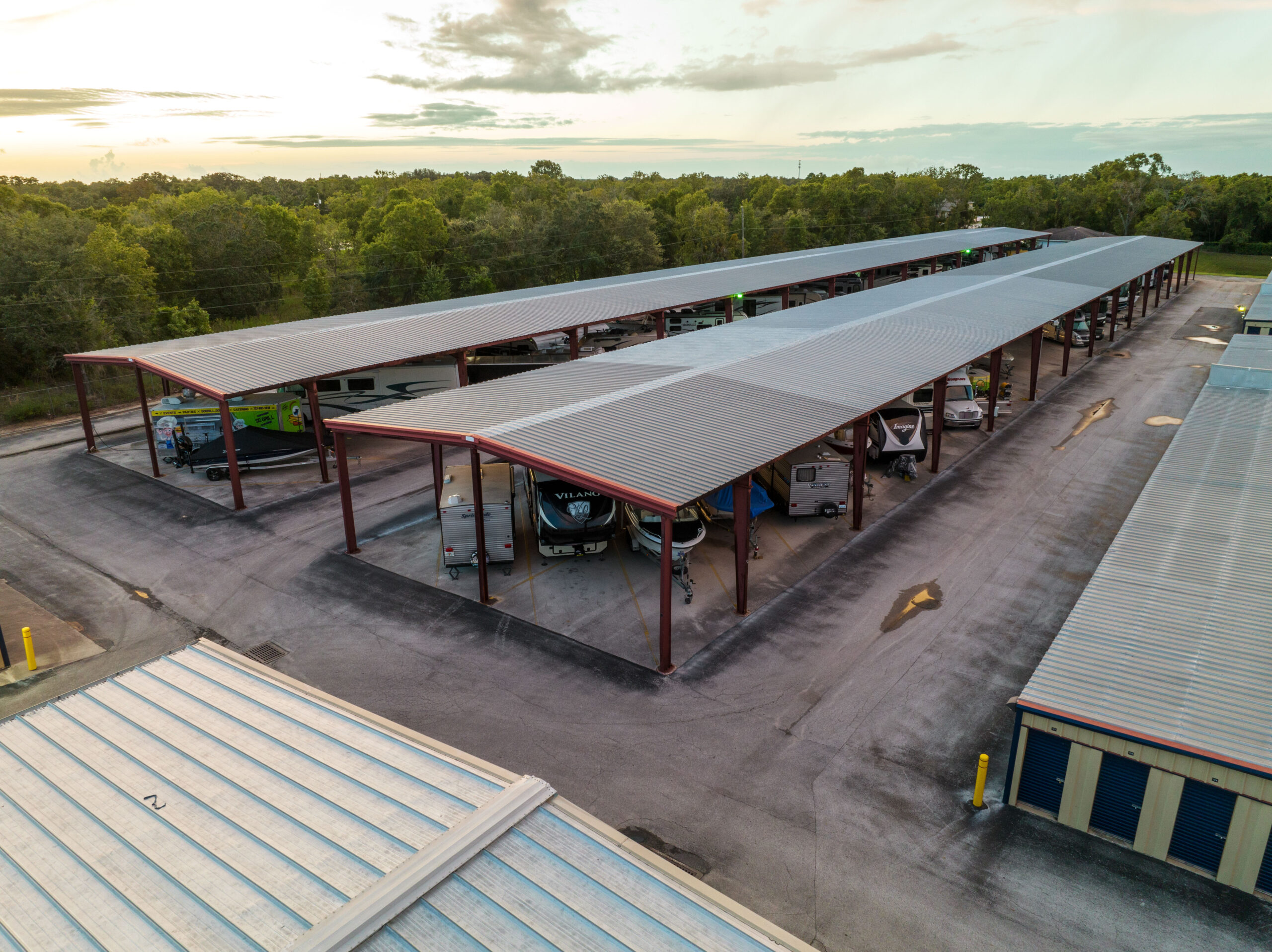 Aerial view of covered RV, boat, and vehicle storage, plus drive-up self-storage units at a facility.