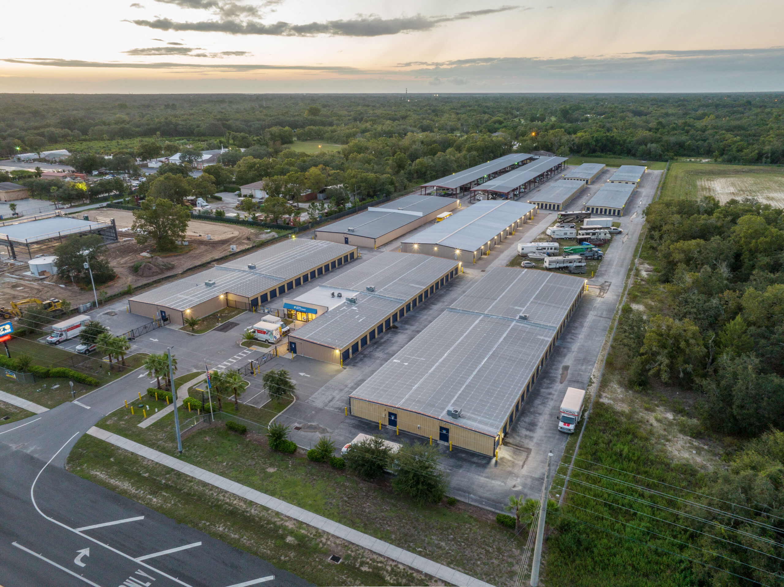 Aerial view of Spring Hill self storage units, RV & boat parking, office building, and solar roofs at dusk.